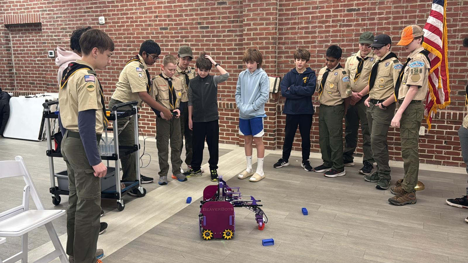 Scouts and students watch a BeaverBots competition robot demonstration during a FIRST awareness event.