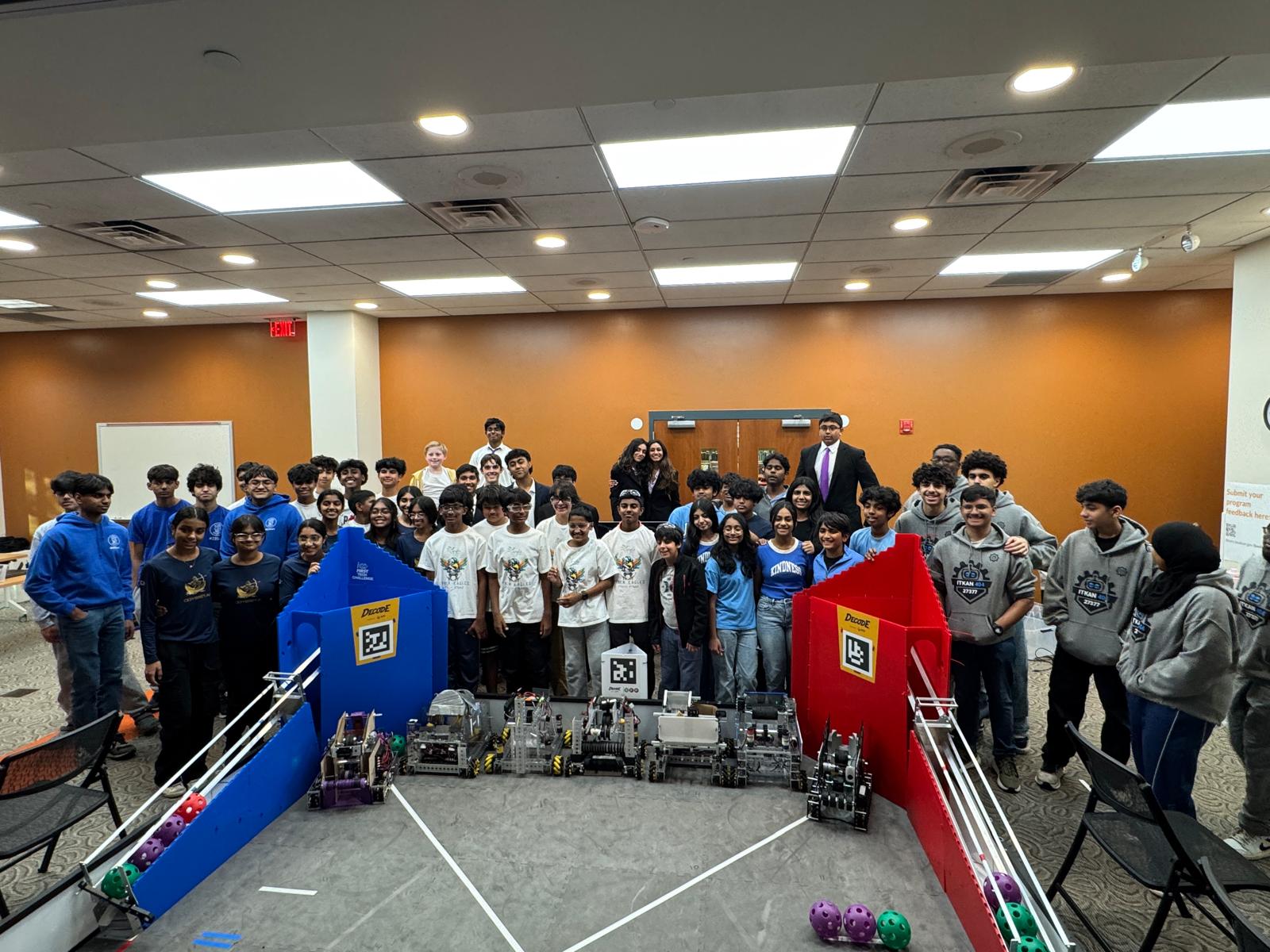 Robotics teams stand behind their competition robots on a complete FTC field.